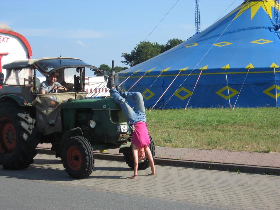 Eine Person macht einen Handstand an einem Traktor B5ec91aa40fce43b023a099c9877288e453d0634